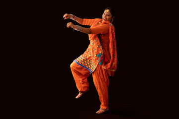 A woman in Giddha costume depicting a dance step with hand gestures.	