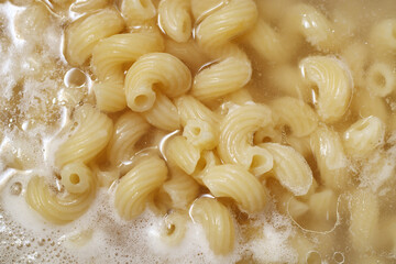 Close up of spiral pasta or cavatappi boiling in water in pan, top view.