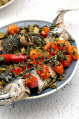 cavala cozida com ervas e tomates cereja está em um prato.
