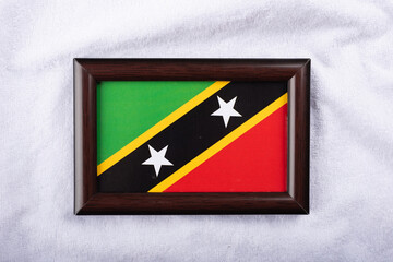 Saint Kitts and Nevis flag in a realistic frame on white cloth background flat lay photo.