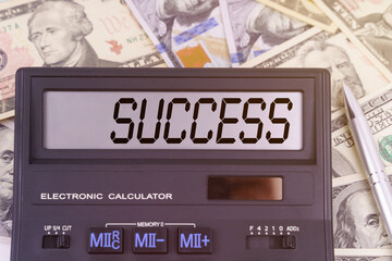 On the table are dollars and a calculator on the electronic board which says SUCCESS