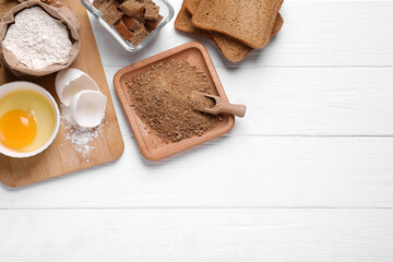 Fresh breadcrumbs, flour and egg on white wooden table, flat lay. Space for text