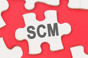 Fototapeta premium On a red background, among white puzzles lies a puzzle with the inscription - SCM