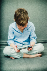 Fototapeta premium boy on the couch with a phone