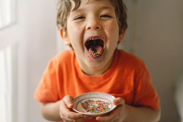 Cute boy eats and plays with Easter sprinkles.