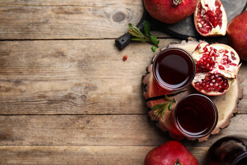 Pomegranate juice and fresh fruits on wooden table, flat lay. Space for text