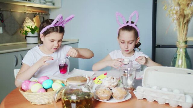Little girls wearing bunny ears painting eggs on Easter day