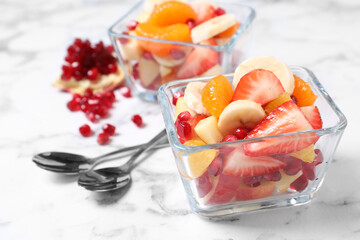 Delicious fresh fruit salad on white marble table, space for text