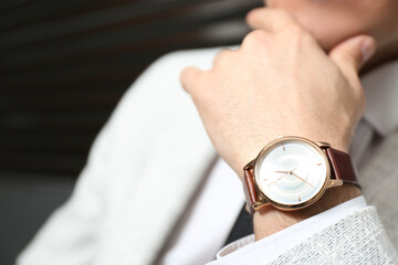 Businessman with luxury wrist watch on blurred background, closeup