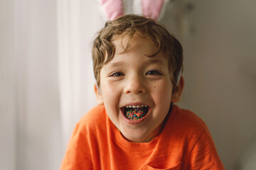 Cute boy eats and plays with Easter sprinkles.