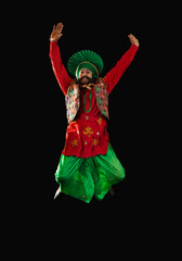 A Bhangra Dancer jumping with hands up to perform a dance step.	