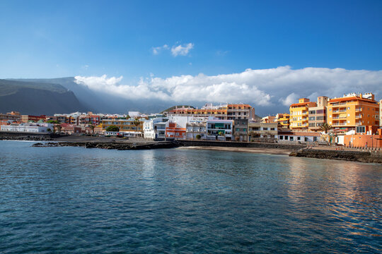tranquil town on the eastern coast of the island with a small neat beach and calm and smooth waves, with few people passing by in Puertito de Guimar, Tenerife, Canary Islands, Spain