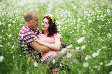 Couple in love guy and girl in a field of white daisies and green grass