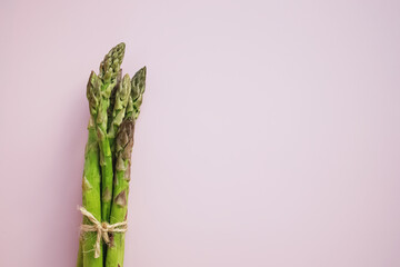 Bunch of raw ripe green asparagus on pink background