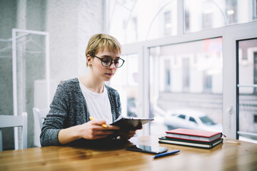 Young woman reading documents on clipboard