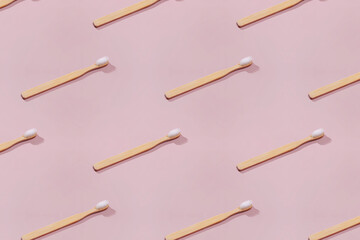 Pattern with wooden tooth brushes on pink background.