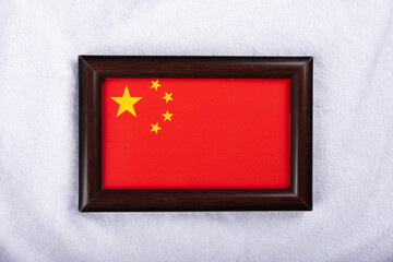 China flag in a realistic frame on white cloth background flat lay photo