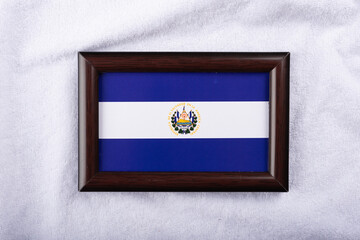  El Salvador flag in a realistic frame on white cloth background flat lay photo
