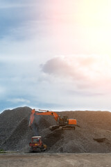 A heavy excavator and a bulldozer are working in a crushed stone factory.