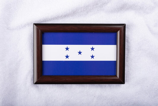 Honduras flag in a realistic frame on white cloth background flat lay photo