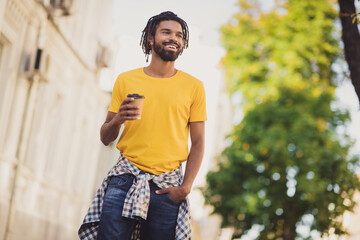 Photo portrait of young man smiling enjoying street walk in sunny day along green streets drinking hot beverage