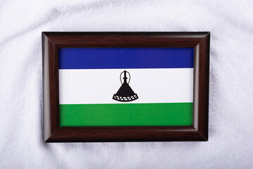 Lesotho flag in a realistic frame on white cloth background flat lay photo