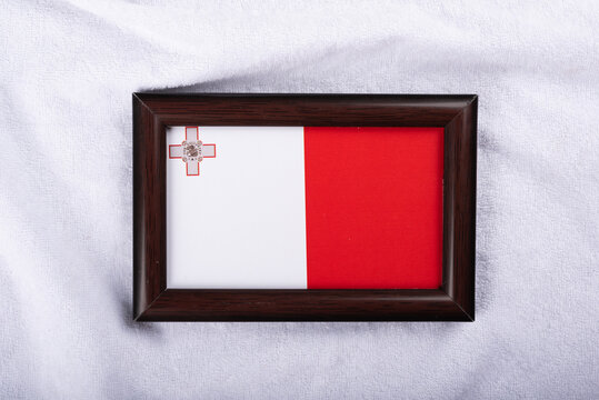 Malta flag in a realistic frame on white cloth background flat lay photo