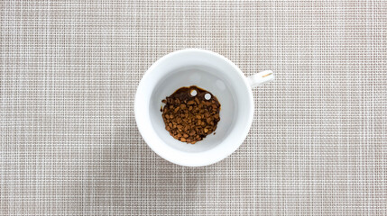 Instant coffee granules in a mug with sweetener tablets.