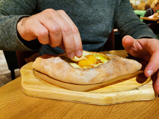 a men in a restaurant eats Georgian khachapuri in Adjarian style