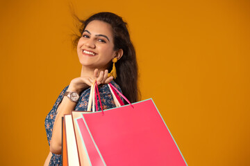 A young woman standing with carry bags.	