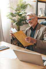 Positive judgment. Senior man opens a mailing letter with a smile. An experienced lawyer won the...