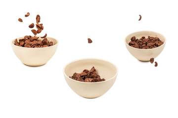 Chocolate corn flakes falling to the white bowl isolated on white. Motion.
