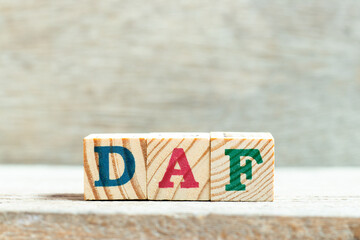 Alphabet letter block in word DAF (Abbreviation of Delivered at frontier) on wood background