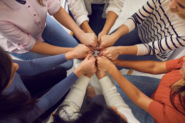 Top view close up of women's hands holding each other in group therapy or in a session with a motivational trainer. Concept of women's community, psychological help, trust and support.