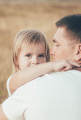 Fototapeta premium little girl hugs daddy by the neck and smiles