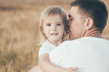 little girl hugs daddy by the neck and smiles