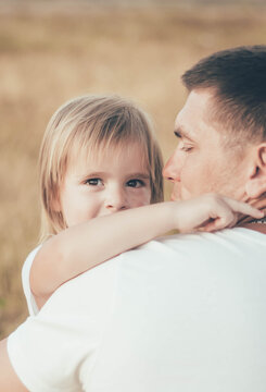 little girl hugs daddy by the neck and smiles