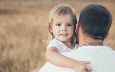 Fototapeta premium little girl hugs daddy by the neck and smiles