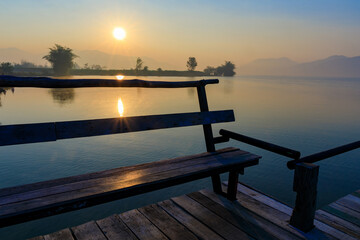 Fototapeta na wymiar Wooden seat or bench on the wooden bridge on the lake with Sunrise time.
