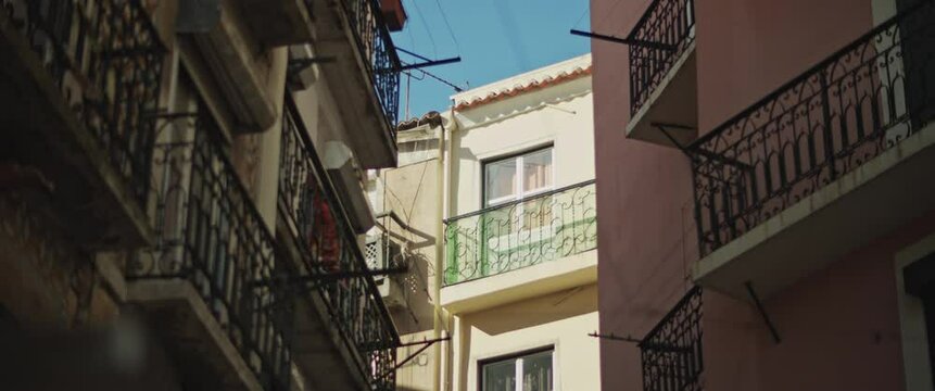 Narrow street in Lisbon with beautiful picturesque colorful apartment buildings. Slow motion.