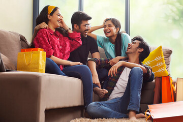 A Group of youngsters talking happily in living room after a shopping spree.	
