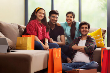 A Group of youngsters sitting happily in living room after a shopping spree.	