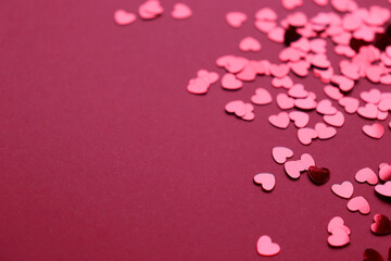 Sparkling confetti in the shape of a heart is scattered on a red background. The concept of love. A greeting card. Valentine's Day