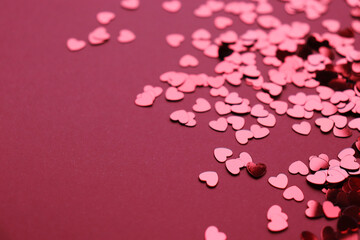 Sparkling confetti in the shape of a heart is scattered on a red background. The concept of love. A greeting card. Valentine's Day