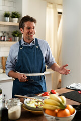 Young man preparing vegetable salad in the kitchen. Happy man making healthy meal