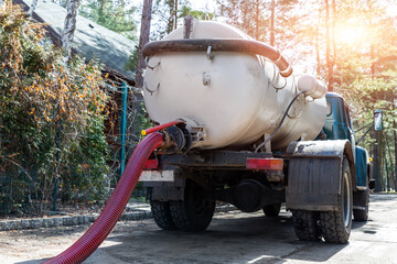 Close-up pipe hose of sewage truck car engine emptying home sewerage tank. Septic cleaning vacuum...
