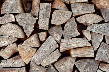 Lots of chopped firewood on a pile close up. Harvesting firewood for the winter. Dry firewood for a fireplace. Decorative wall from firewood.