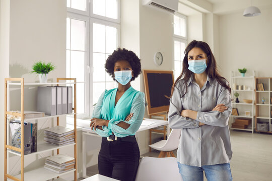 New normal office, return to work after covid-19 lockdown. Portrait of interracial businesswoman wearing protective face mask with arms crossed on chest standing in office looking at camera