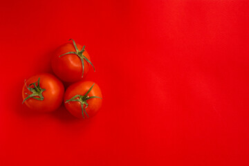 red tomato with green stalk on red background