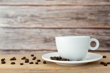 A white hot coffee cup with a saucer is placed on a wooden plate and on a wooden background.